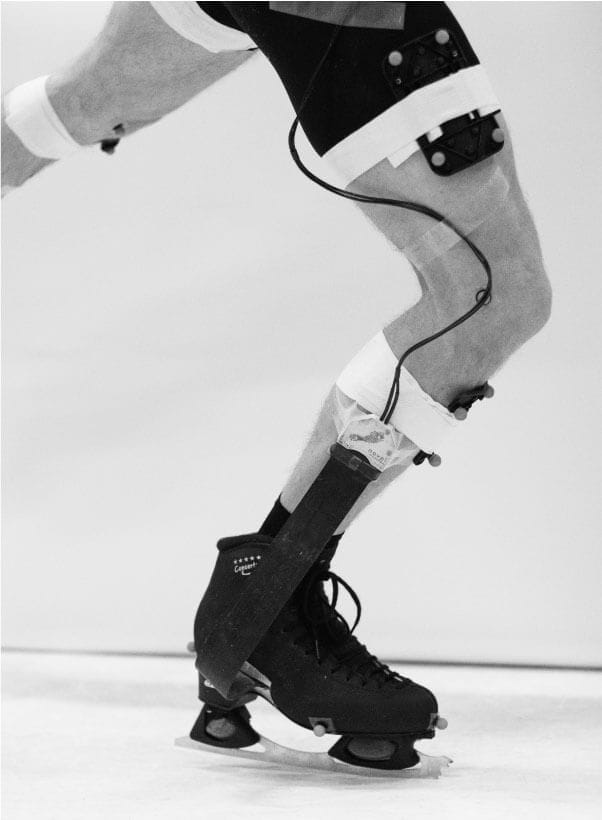 Landing impact in a laboratory, research in figure skating biomechanics—skater landing with shock-absorbing blades, black and white image.
